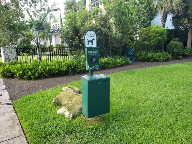 A pet waste station installed on the landscaped grounds of an HOA community common area