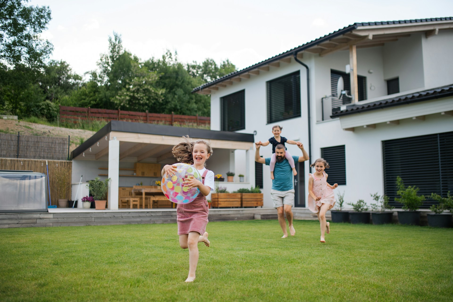 Family playing together on a clean backyard lawn in front of their home